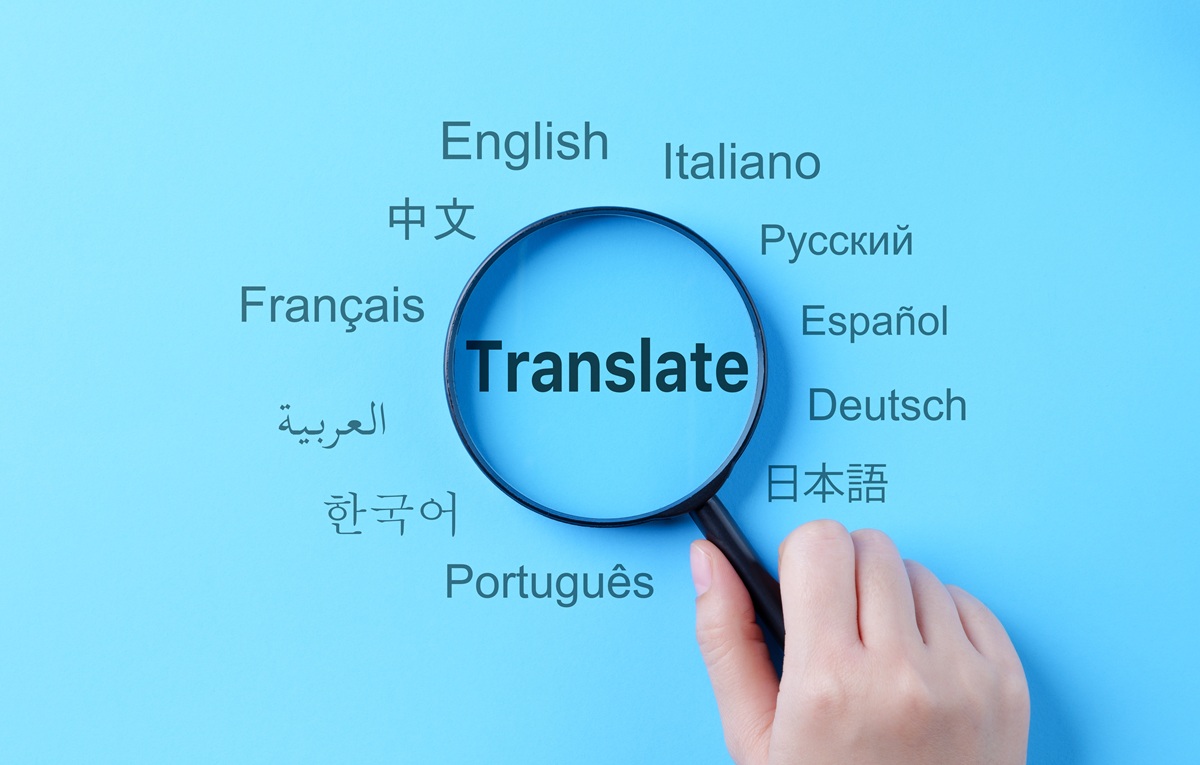 Une main tenant une loupe au-dessus du mot « Translate», situé au milieu de plusieurs langues différentes